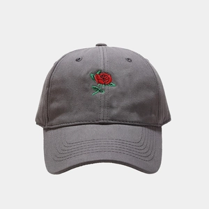 Dettaglio del ricamo a rosa rossa su un cappellino da baseball in cotone grigio scuro