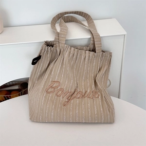 Detail of striped canvas tote bag with Bonjour embroidery and drawstring closure
