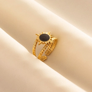 18k gold plated stainless steel sun ring with black enamel center on beige fabric