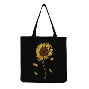 Detail of sunflower skull print on black canvas tote bag with 'You are my sunshine' text
