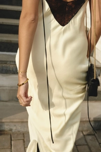 Detail of elegant cream satin dress showing black lace back with a luxury chain bag