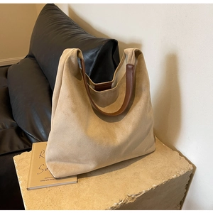 Detail view of khaki faux suede shoulder bag with brown leather strap on stone surface
