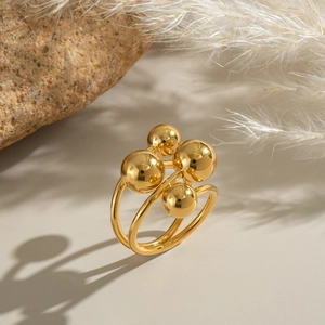 Modern gold multi-bead geometric ring with a polished mirror finish on a warm pedestal