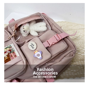 Close-up of pink school backpack with transparent pocket, plush bear and cute badges