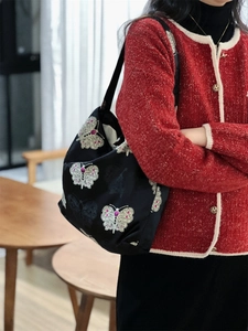 Detail of black jacquard tote bag featuring intricate white butterfly embroidery pattern