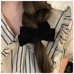 Detail of a black velvet bow hair tie styled on a braided hairstyle for a vintage look