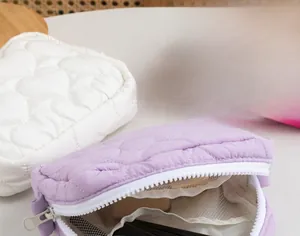 Close-up of heart-quilted candy color cosmetic bags with white zippers and mesh pockets