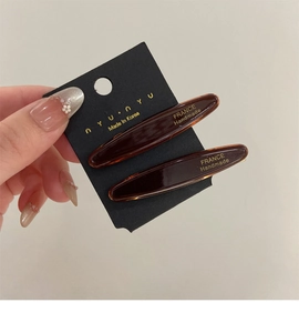 Gros plan de barrettes en acétate ambré avec inscription dorée France Handmade sur carte