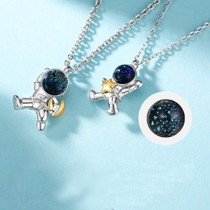 Detailed close-up of astronaut pendant with gold moon and star accents on silver chain