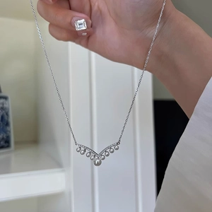 Macro shot of V-shaped pearl necklace with zircon accents on a polished silver chain