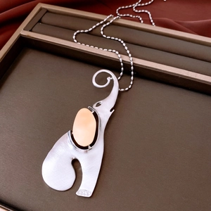 Close-up of matte silver elephant pendant with inlaid oval stone on dark jewelry tray