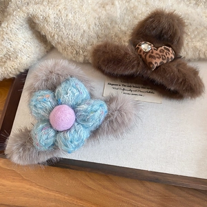 Detail of plush faux fur hair claws featuring leopard heart and woven blue flower patterns