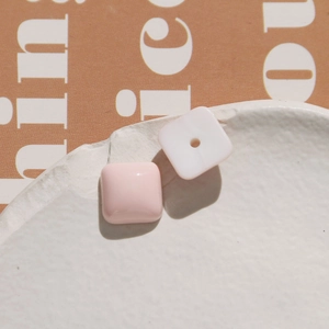 Close-up of pink and white resin square charms on an artistic white ceramic plate