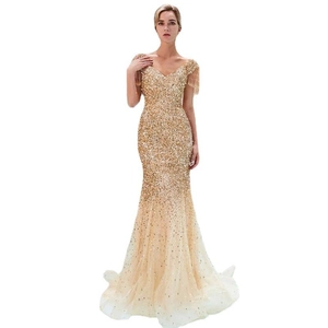 Dettaglio dell'abito da sera in paillettes dorate con scollo a V ed eleganti frange sulle spalle