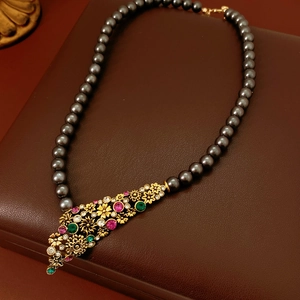 Détail du pendentif fleur vintage serti de gemmes sur collier en perles grises