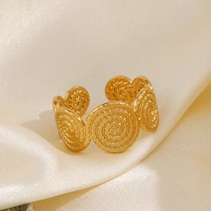 Minimalist golden spiral stainless steel ring on elegant beige silk fabric background