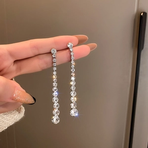 Close-up of sparkling silver tassel earrings with crystal rhinestones in hand