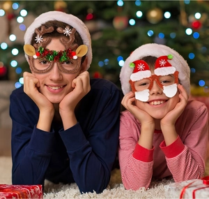 Children wearing festive Christmas glasses with reindeer antlers and Santa hat decorations