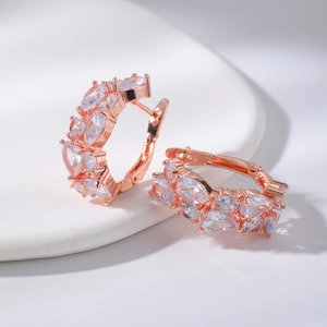 Détails de boucles d'oreilles or rose serties de zircons poire sur un plateau blanc