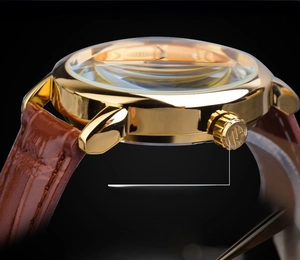 Detail of gold stainless steel watch case with leather strap and domed mineral glass