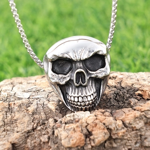 Macro shot of polished silver pirate skull pendant with detailed metal texture and steel chain