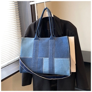 Detail of color-block denim tote bag with contrast stitching on black blazer