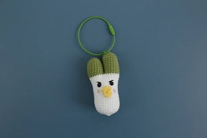 Detail of hand-knitted scallion bag charm with soft wool texture and green metal ring