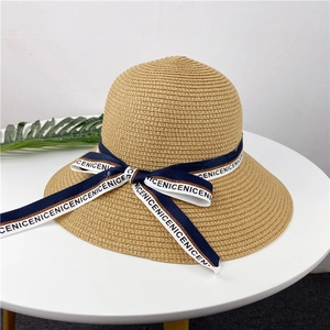 Détail d'un chapeau de paille tissé avec un ruban nœud bleu et blanc sur fond blanc
