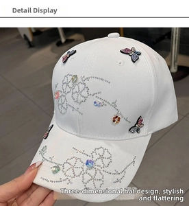 Detailed view of colorful rhinestone butterfly patterns on white baseball cap fabric