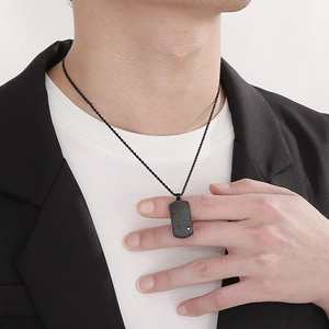 Collier minimaliste en acier inoxydable noir avec gravure porté par un mannequin homme