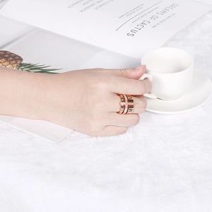 Detailed view of layered rose gold titanium ring with Roman numerals and crystals