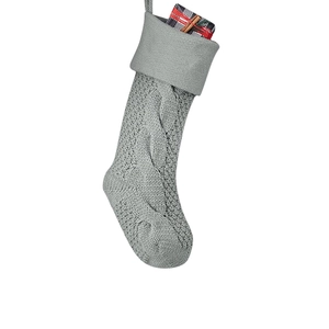 Detailed knit pattern on gray Christmas stocking featuring a small plaid gift box insert