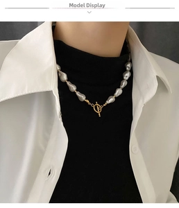 Detailed view of baroque pearl necklace with gold T-bar toggle clasp on model dress