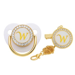 Detail of white and gold baby pacifier set with rhinestone letter W and matching clip