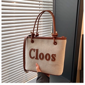Detail view of canvas tote bag with brown leather handles and Cloos letter embroidery