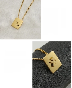 Macro detail of 18K gold plated square zodiac pendant showing Capricorn and Sagittarius symbols