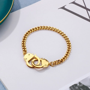 Detailed close-up of a gold Cuban link bracelet featuring an interlocking handcuff charm