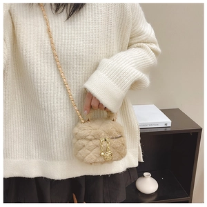 Detail of plush quilted crossbody bag with gold chain strap and floral charm on a model