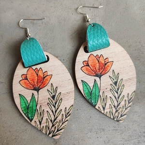 Detail of bohemian wood earrings with sunflower patterns and teal leather accents