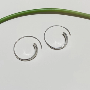 Detail of silver hoop earrings with a sleek curved design and a high-polished metallic finish