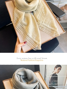 Dettaglio di sciarpe di seta beige e grigie con eleganti bordi in pizzo molto larghi
