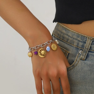 Detailed view of mixed metal bracelet with sun, moon, and star charms on model's wrist