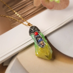 Macro view of green crystal pendant with black rhinestones and colorful chakra stones