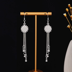 Detail of silver sun flower earrings with long tassels on a professional jewelry display