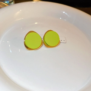 Macro view of neon green enamel stud earrings with irregular gold wavy metallic edges