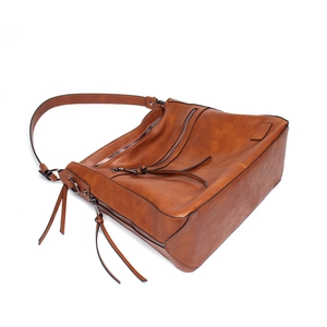 Detail view of vintage brown leather tote bag with long tassel zippers and multiple pockets