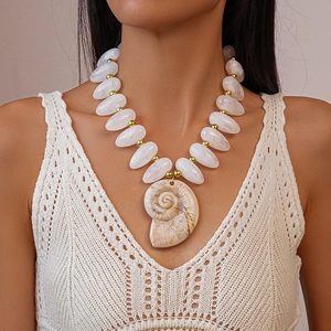 Detail shot of acrylic beads and a gold conch shell pendant on a holiday necklace