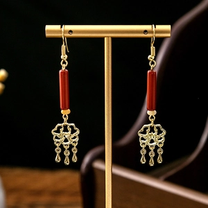 Detail showing Chinese style earrings with red beads and golden hollow flower tassels