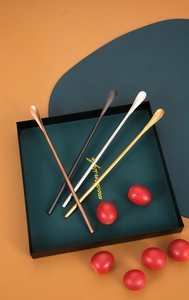 Detailed view of four colorful long-handled stainless steel stirring spoons in a tray