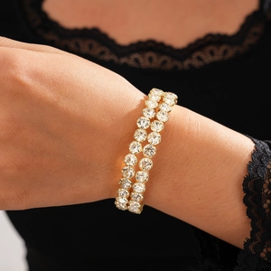 Detail view of a luxury double-row gold-tone bracelet with sparkling white rhinestones